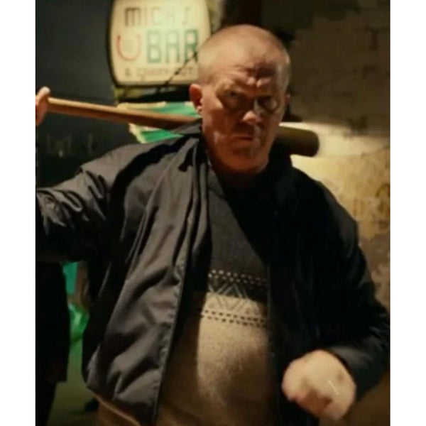 Man holding a baseball bat in a dimly lit room with a sign in the background