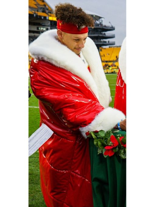 Person wearing a red puffer jacket with white fur trim on a sports field.