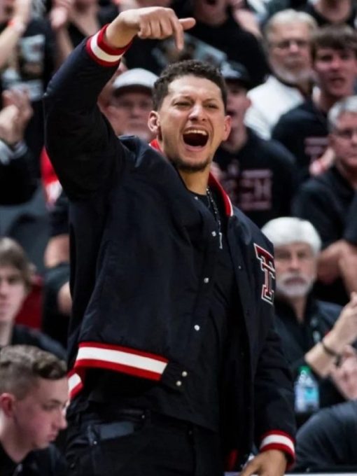 Person in a black jacket with red accents pointing upwards in a crowd