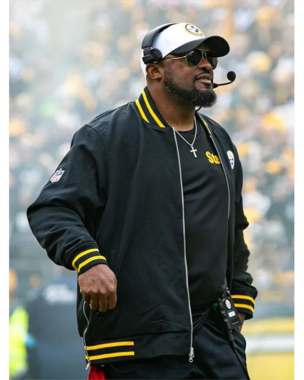 Person wearing a black jacket with yellow accents and a headset, standing on a field.