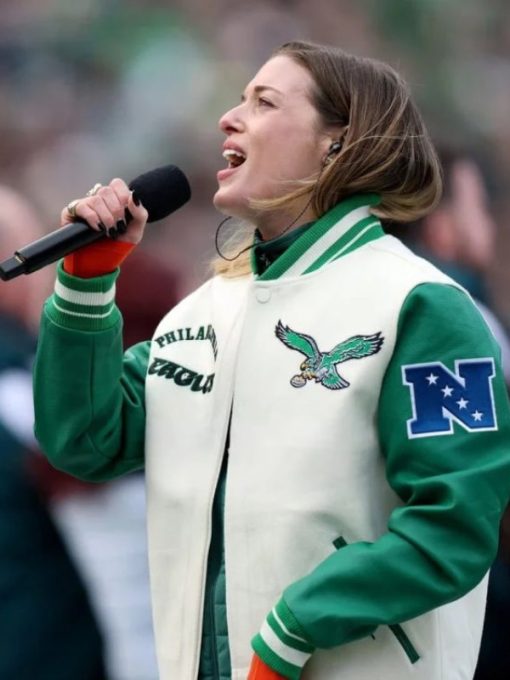 Person wearing a green and white jacket with sports team logos, holding a microphone.
